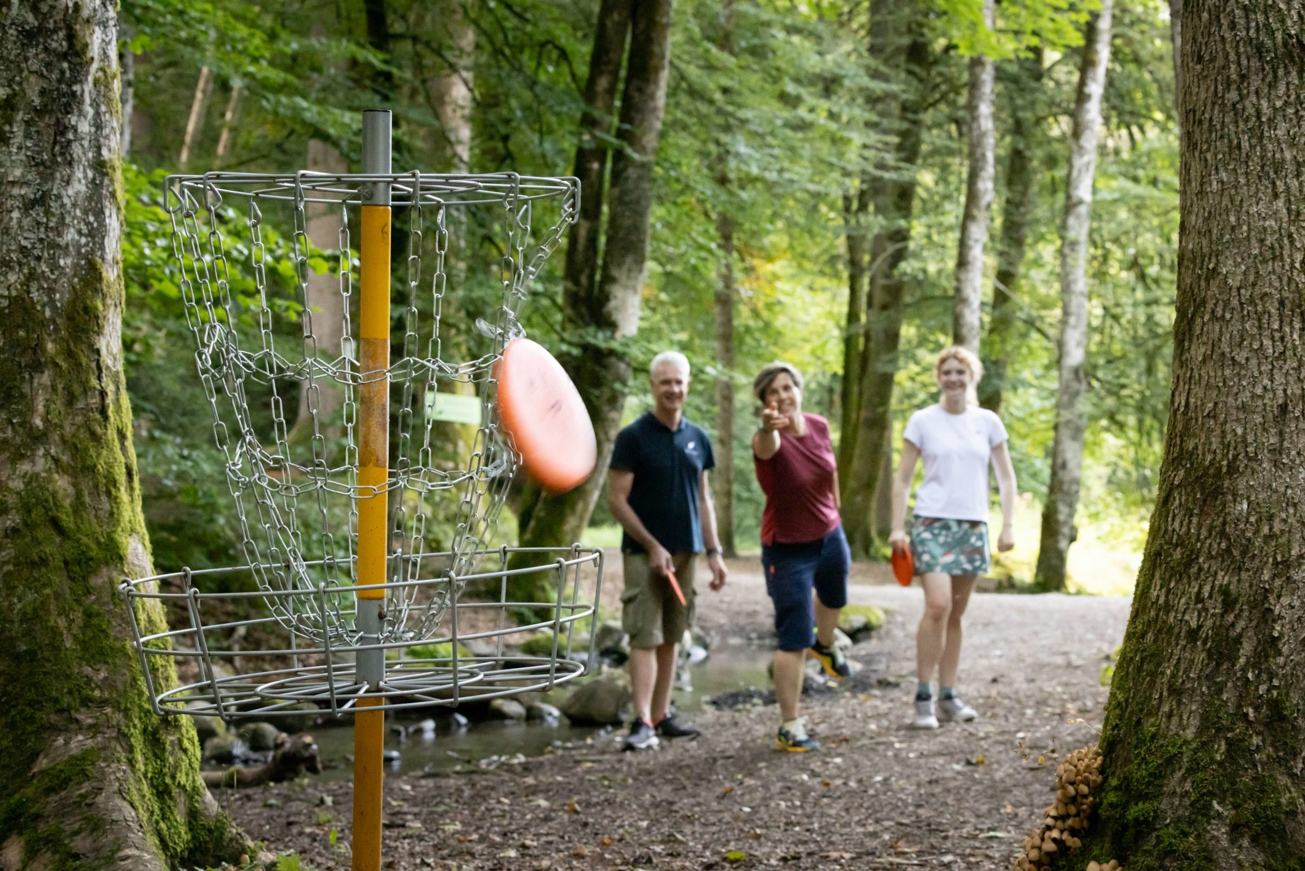 groupe de trois personnes jouant au disc golf