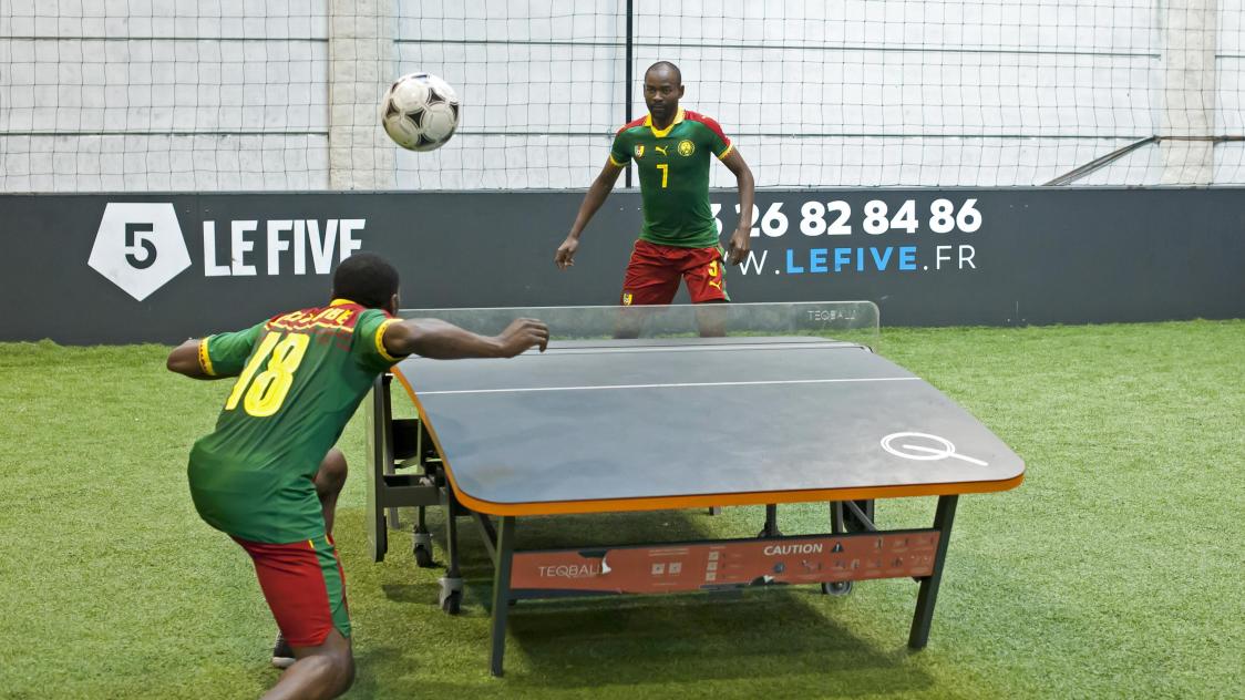 deux personnes faisant une brésilienne avec une table de ping pong et un ballon de foot